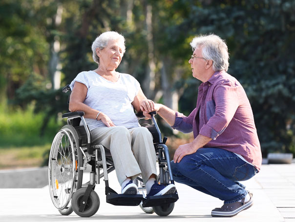 Man sits next to an older woman in a wheelchair