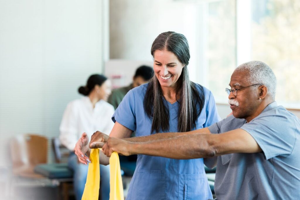 Physical therapist helping older man with strengthening exercises.