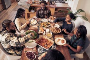 Family sitting around a table enjoying a large meal.