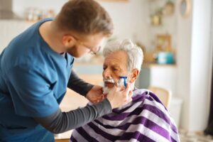 Home care aide helps older man with shaving his face.