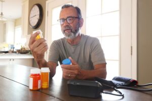 Older man reads the labels on multiple medication bottles