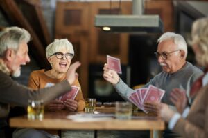 Group of adults playing cards and having fun at an adult day health care center.