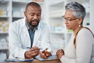 Pharmacist talks to an older woman about medication safety in the summer.