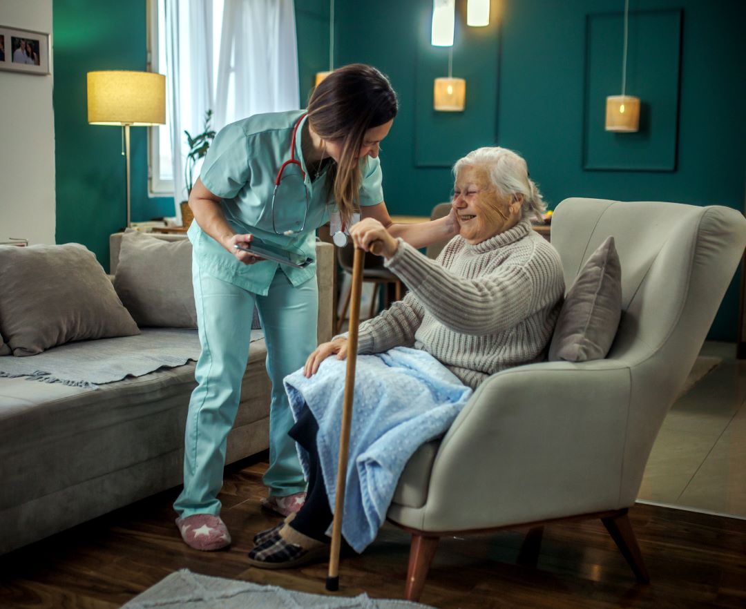 A home health care professional assists an older woman in her home.