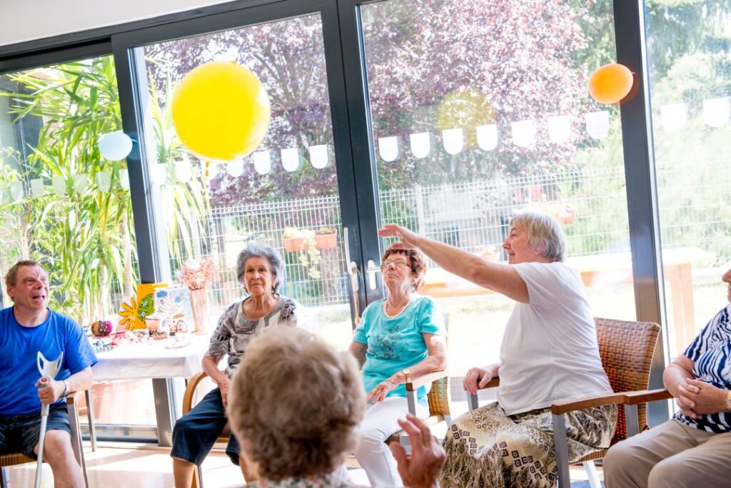 Group of older adults participate in balloon volleyball while at adult day health care.