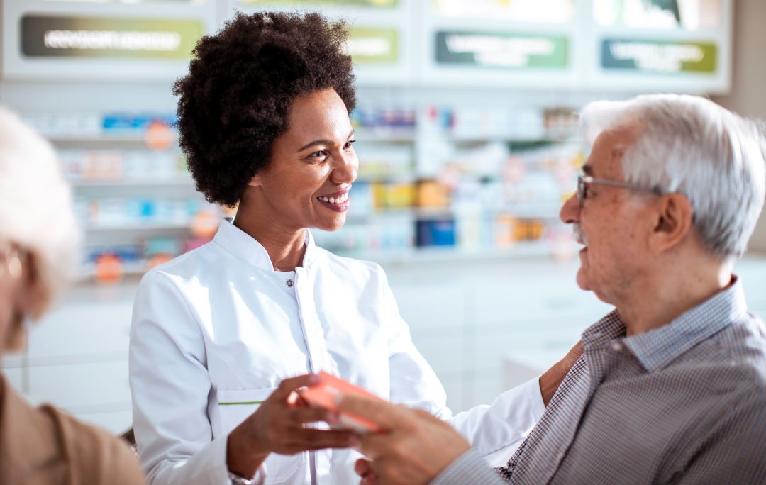 A pharmacist helps an older man with medication during flu season.