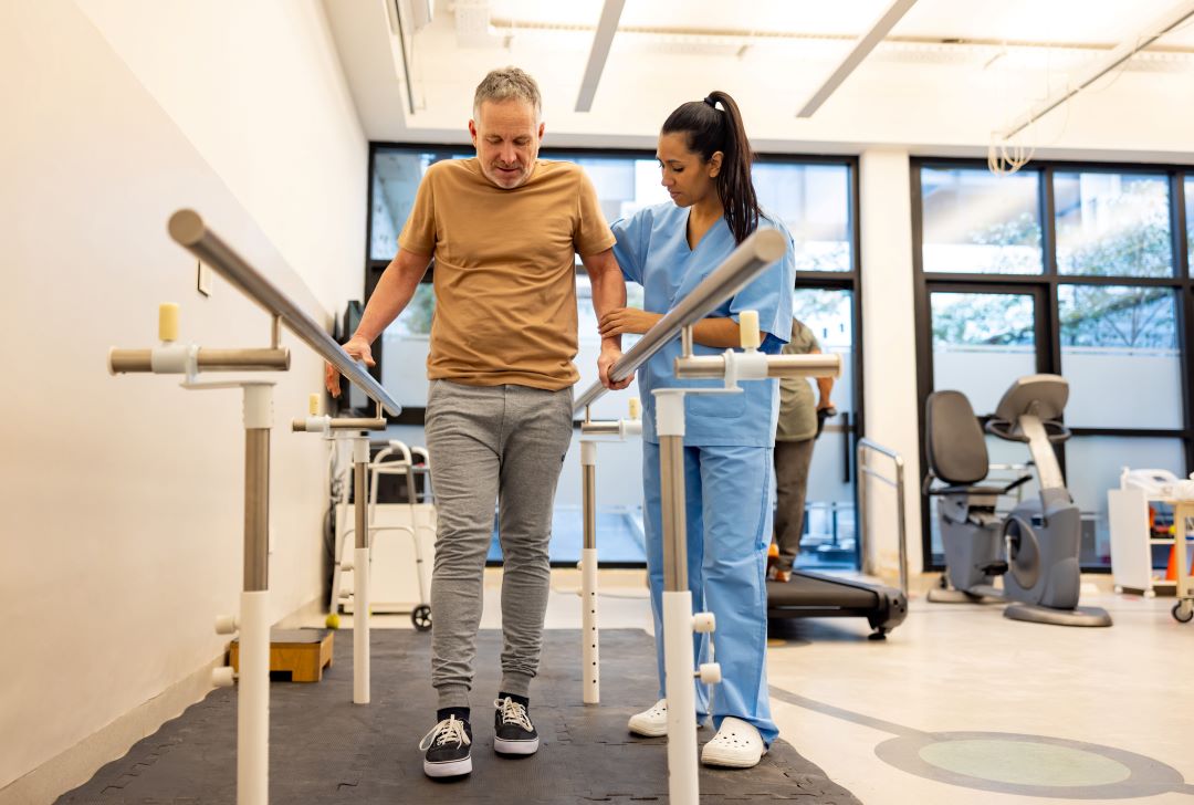 A physical therapist assists a man recover after surgery.
