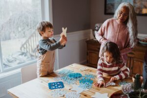 An older woman makes winter decorations with her grandchildren.