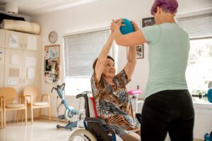A physical therapist helps an older woman with Parkinson's.