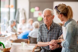 An older man walks with his caregiver.
