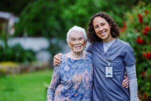 An older woman smiles alongside her caregiver.