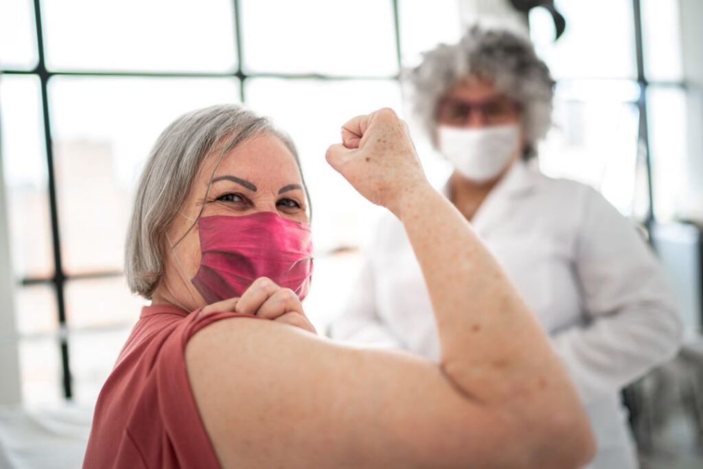 An older woman smiles after getting a vaccine.